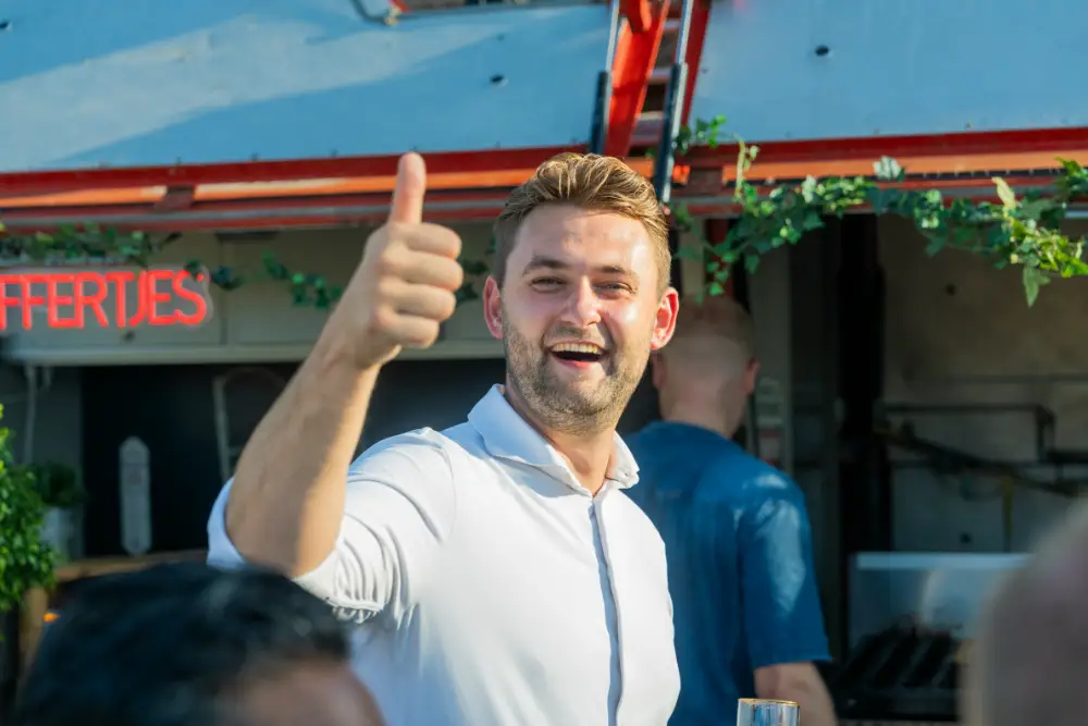 Collega van MBG steekt lachend zijn duim op tijdens een bijeenkomst