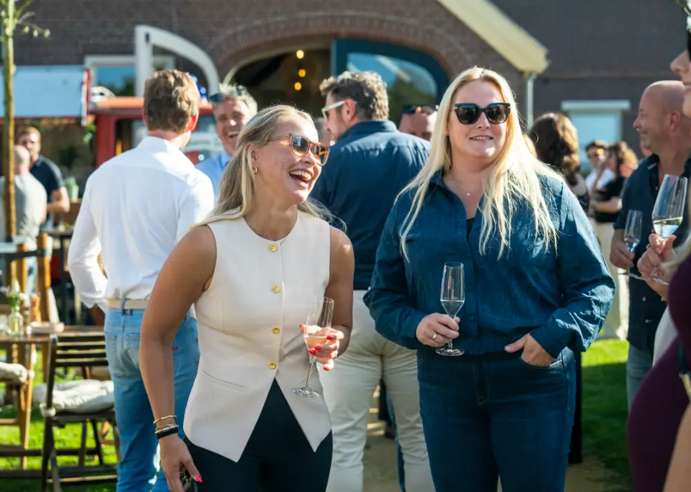 Twee collega's lachend in gesprek tijdens een bijeenkomst