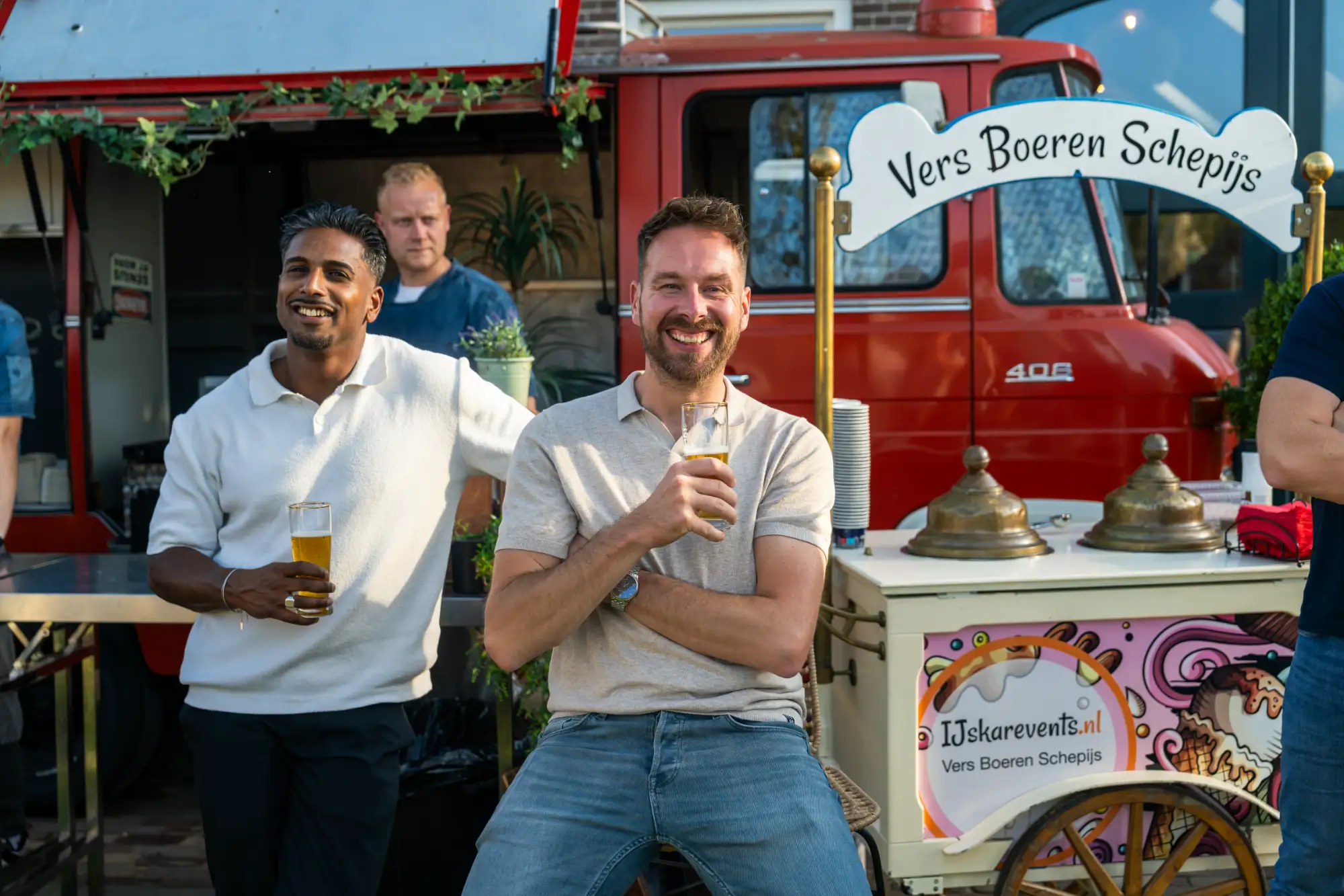Twee collega's van MBG tijdens een bijeenkomst, bij een ijskar en een oude brandweerauto